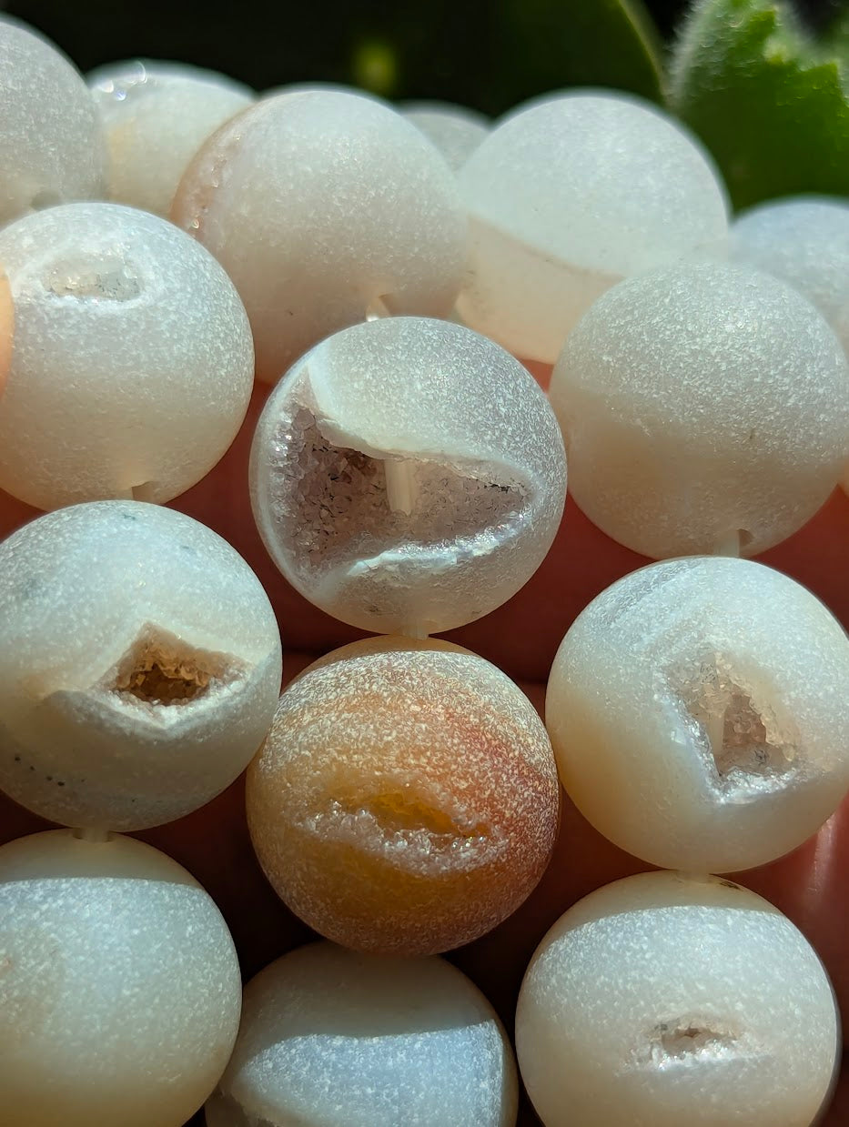 Macro detail of 14mm Agate beads highlighting the sparkling quartz crystals inside the natural vugs.