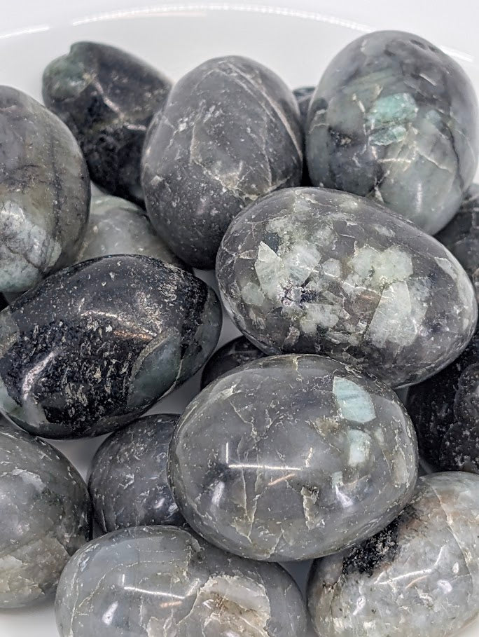 Close-up of emerald tumbled stones showing green and black veining