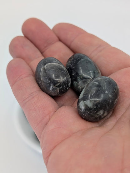 Emerald tumbled stones shown in hand for scale