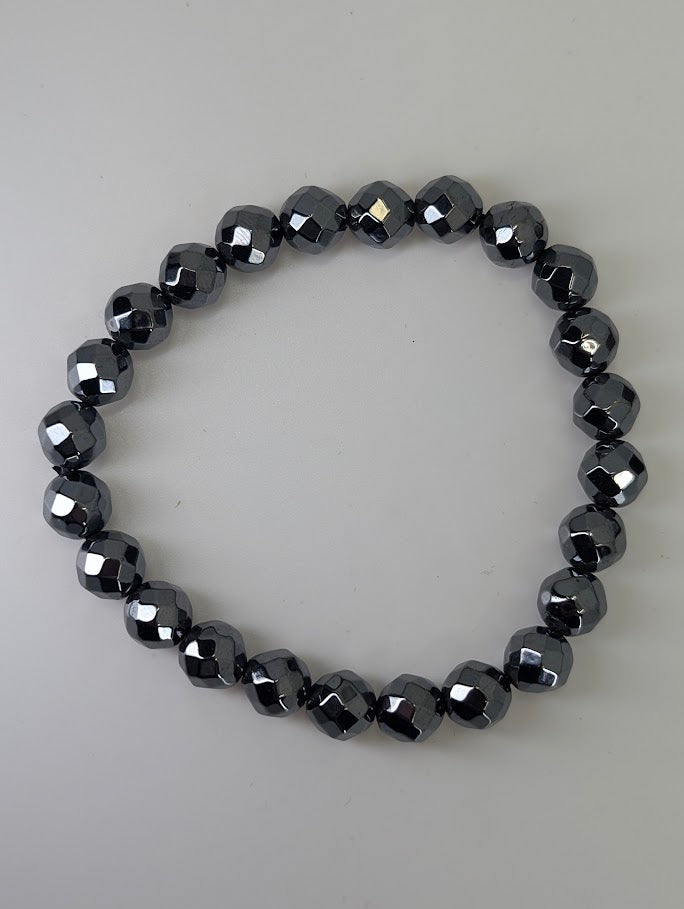 Top-down view of 12mm faceted hematite bracelet on white background