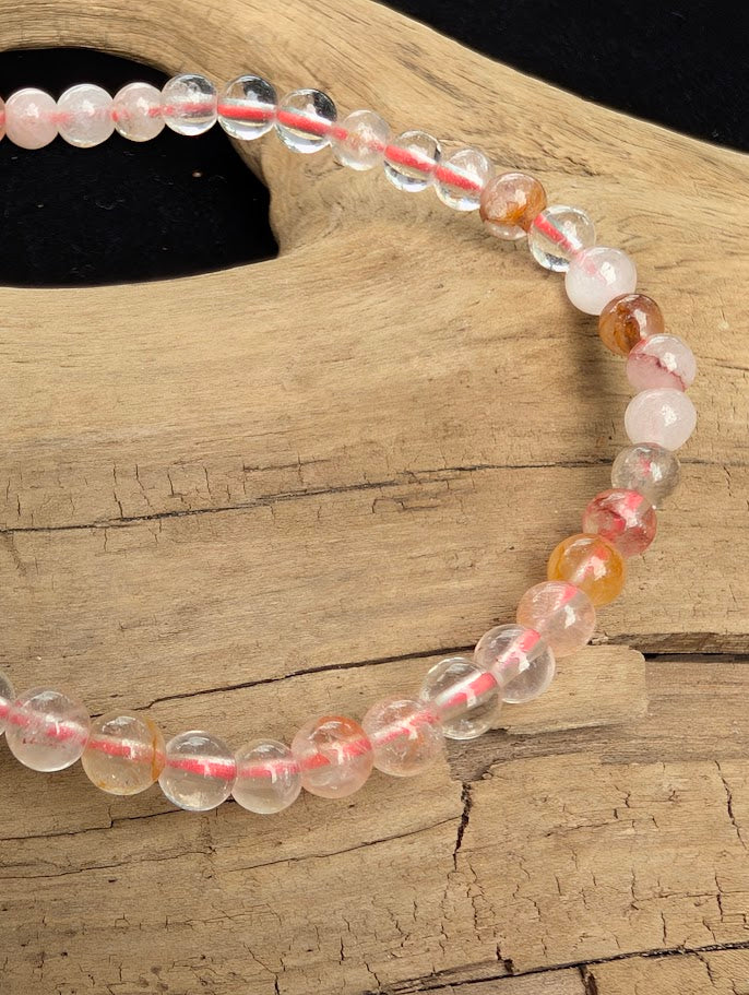 Macro close-up of 4mm polished Fire Quartz beads highlighting the high-gloss finish and natural red hematite "flame" inclusions.