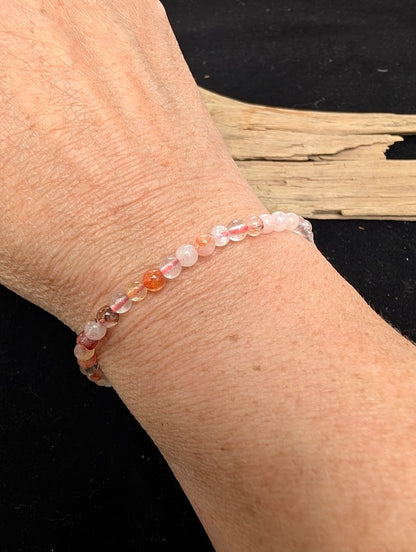 4mm polished Fire Quartz beaded stretch bracelet worn on a wrist for delicate size scale.