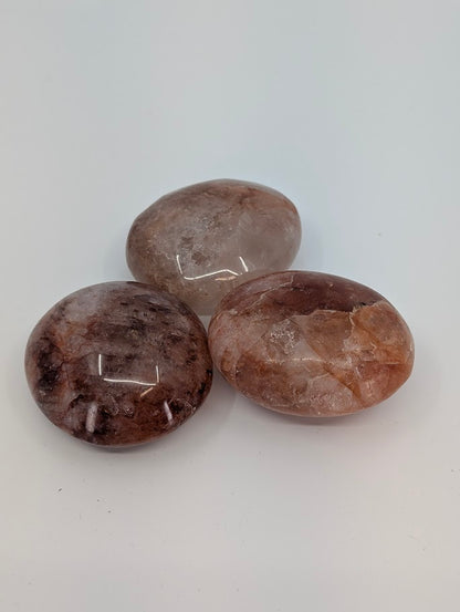 Group of Fire Quartz Palm Stones showing red and clear tones with hematite inclusions