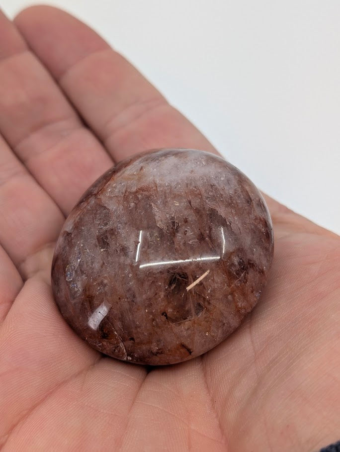 Fire Quartz Palm Stone held in hand showing warm red inclusions and polish clarity