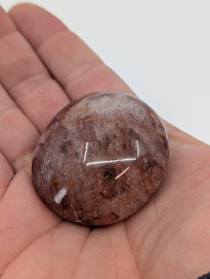 Fire Quartz Palm Stone held in hand showing warm red inclusions and polish clarity
