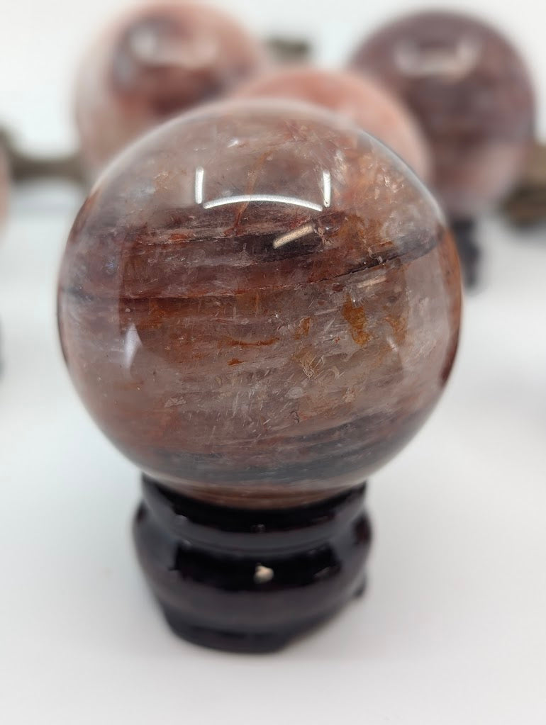Portrait isolation of Brazilian Fire Quartz sphere FQ-16, showing its high optical depth and dark, complex internal hematite pathways under studio lighting.