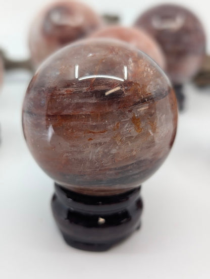 Portrait isolation of Brazilian Fire Quartz sphere FQ-16, showing its high optical depth and dark, complex internal hematite pathways under studio lighting.