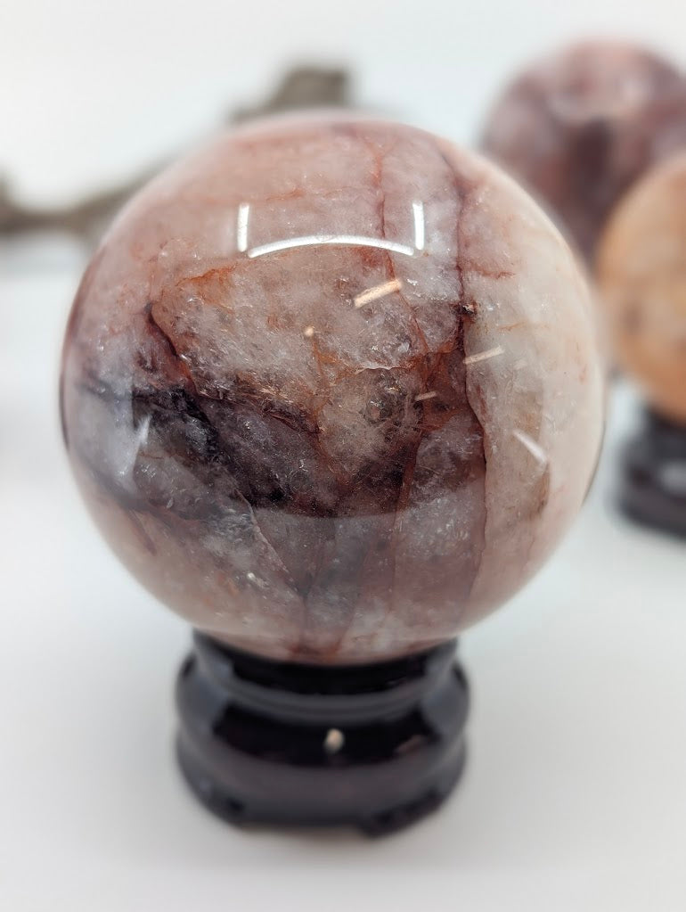 Polished profile view of natural Hematoid Quartz sphere FQ-14 from Brazil, highlighting the subtle iron staining and primary structural line.