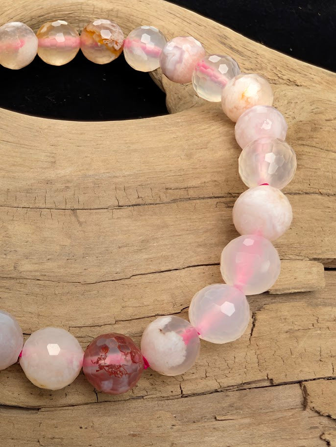 Macro close-up of 8mm faceted Flower Agate beads highlighting the geometric cut and the natural three-dimensional chalcedony blossom formations within the matrix.