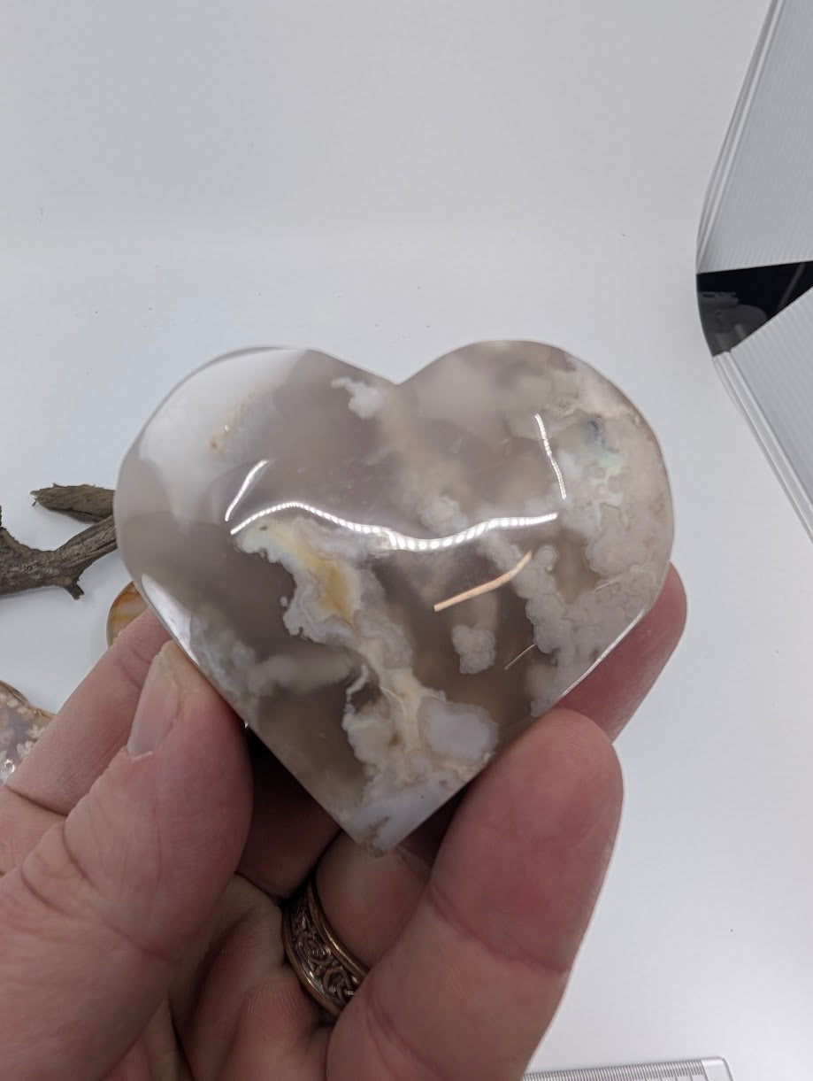 Hand holding Specimen C, a 115g Flower Agate heart with clear petals.
