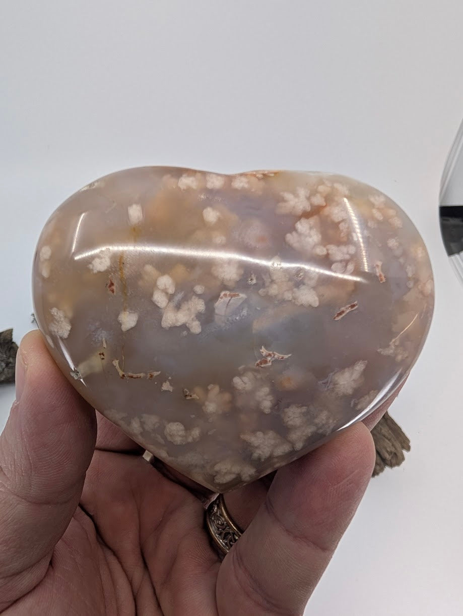 Hand holding Specimen A, a large 255g Flower Agate heart with snowy inclusions.