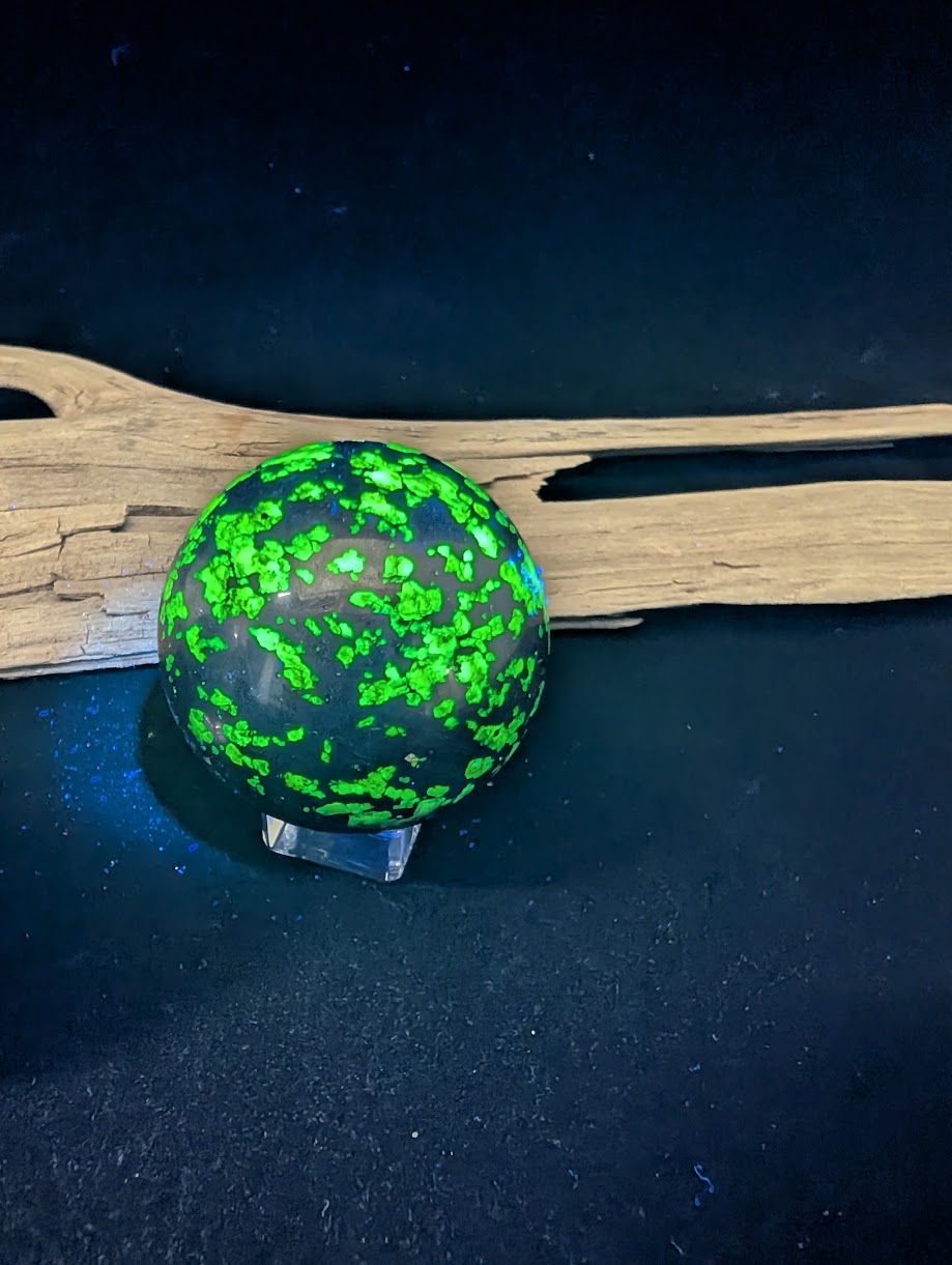 47mm sphere glowing under shortwave UV with distinct neon green and deep blue hydrozincite patches.