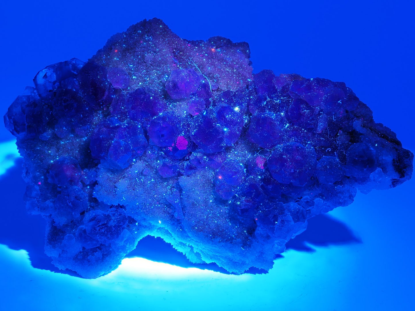 Xia Yang Mine Fluorite specimen glowing bright blue under UV ultraviolet light.