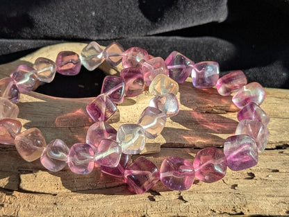 A 10mm Banded Purple Fluorite cube bead stretch bracelet positioned on a neutral presentation surface, demonstrating precise lapidary polish and rich purple colour zoning.