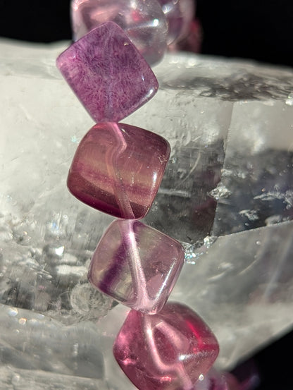 Macro close-up view of polished 10mm Banded Purple Fluorite cubes, highlighting the vitreous surface luster and natural cubic geometry.