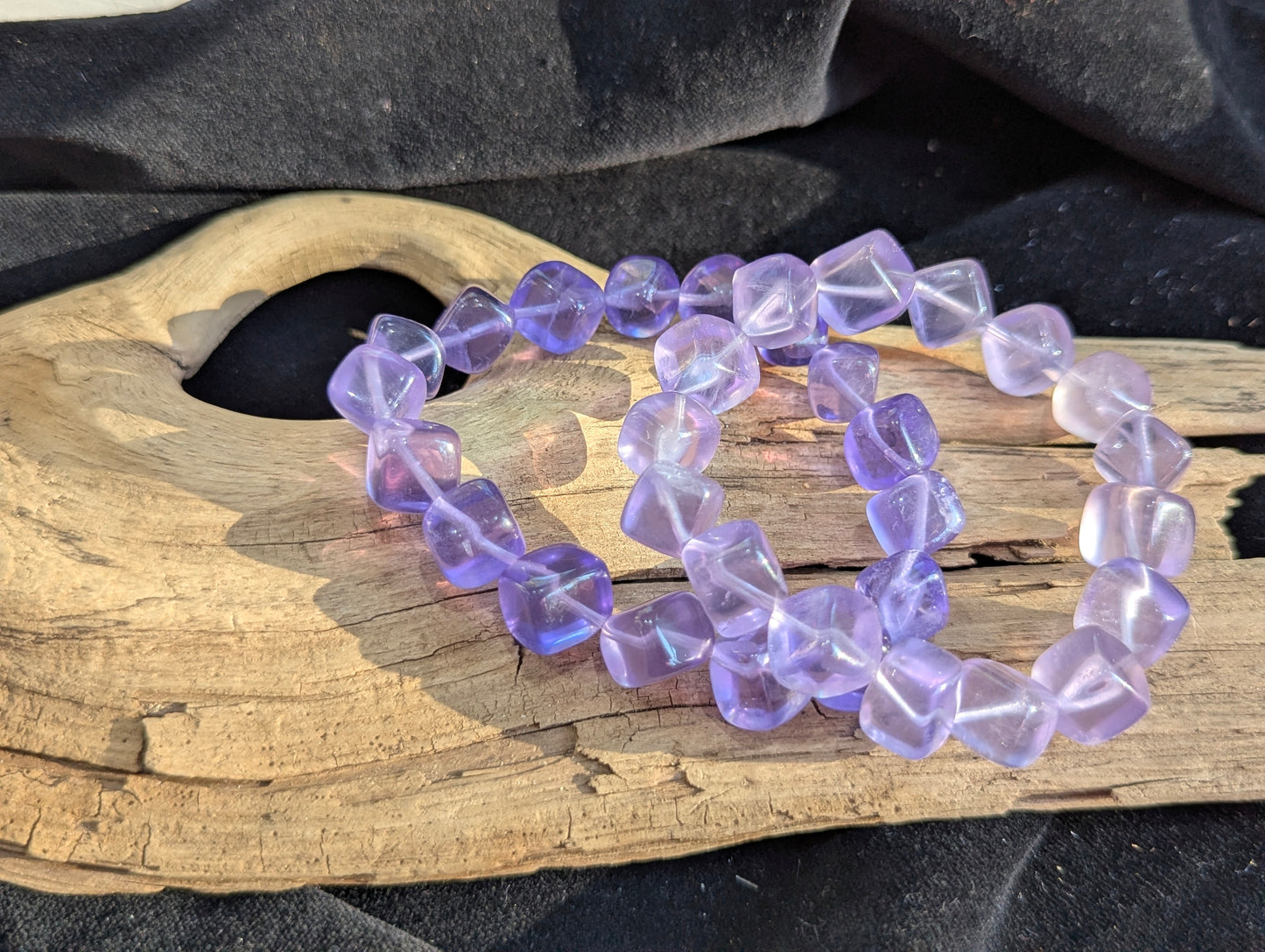A 10mm Lilac Purple Fluorite cube bead stretch bracelet positioned on a neutral presentation surface, demonstrating bead uniformity and soft violet colouration.