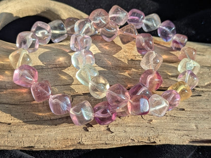A 9mm Pastel Rainbow Fluorite cube bead stretch bracelet resting on a flat presentation surface, showcasing a delicate spectrum of natural pastel hues.