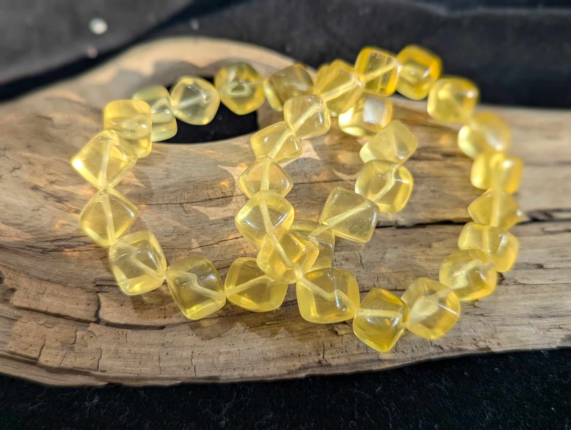 An 11mm Yellow Fluorite cube bead stretch bracelet positioned on a flat presentation surface, showcasing its vibrant golden-yellow saturation and sharp geometric lines.