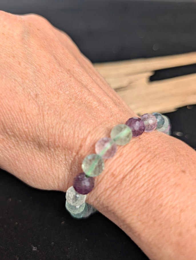 8mm faceted purple and green Fluorite beaded stretch bracelet worn on a wrist for size scale.