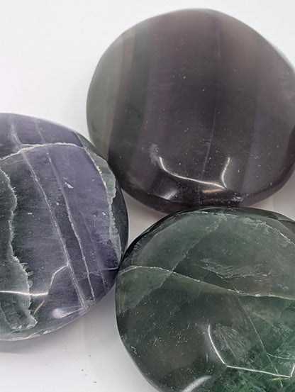 Close-up of polished Fluorite Palm Stones with natural zoning