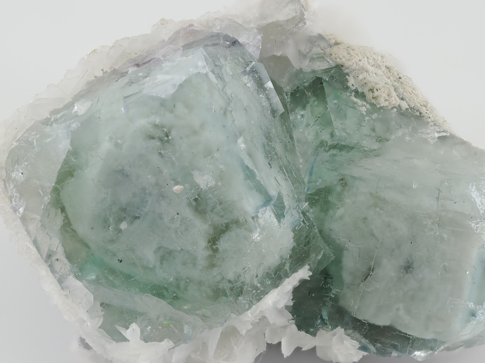 Extreme close-up of the signature waxy, opaque "porcelain" texture and subtle green phantoms within the fluorite cubes.