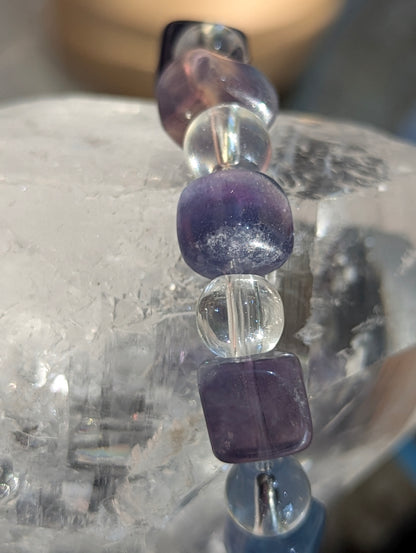 Macro close-up view of polished 9 mm blue fluorite cubes and 8 mm clear quartz spheres, highlighting the vitreous surface luster and exceptional optical clarity of the stones.