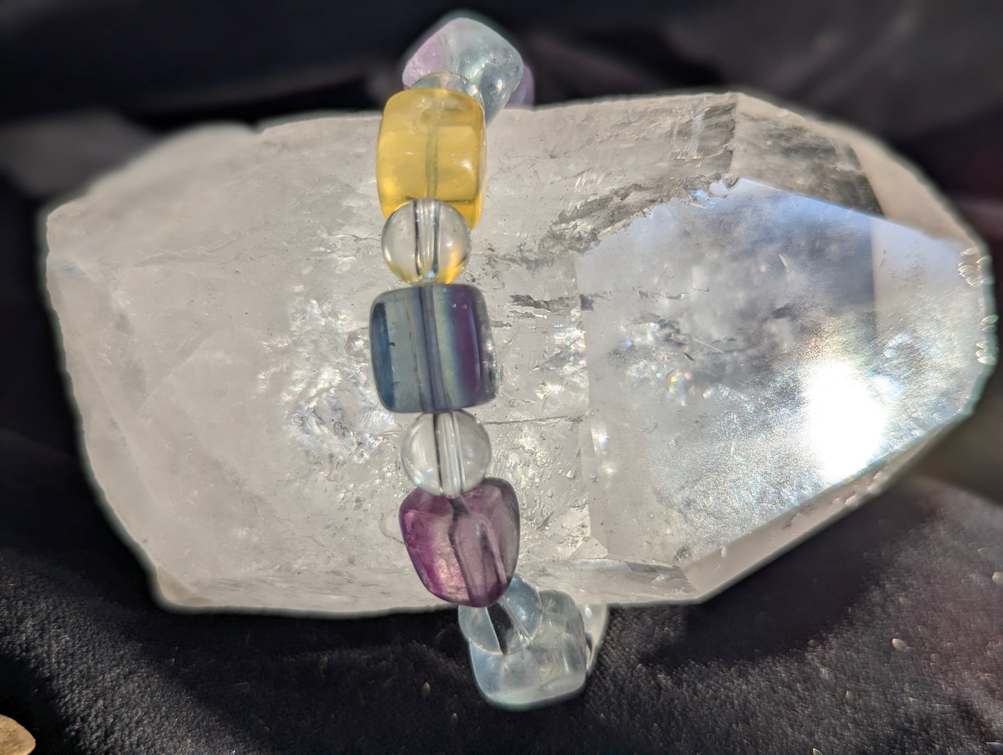 Macro close-up of a mixed-colour fluorite and quartz beaded bracelet, capturing how light refracts brilliantly through the distinct geometric bead forms.