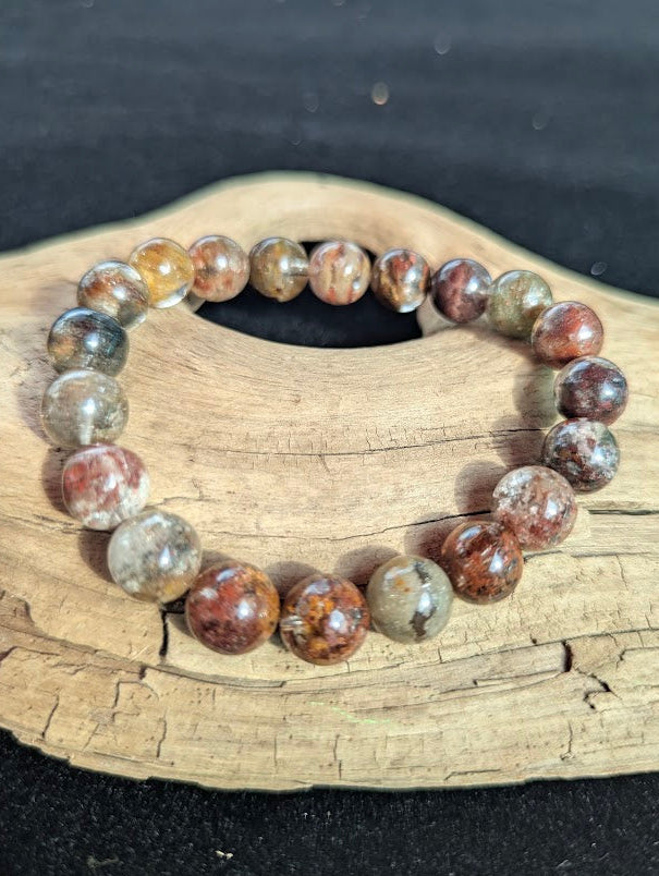 Intuitively selected 10mm AA Grade Four Season Garden Quartz beaded stretch bracelet displayed on driftwood.