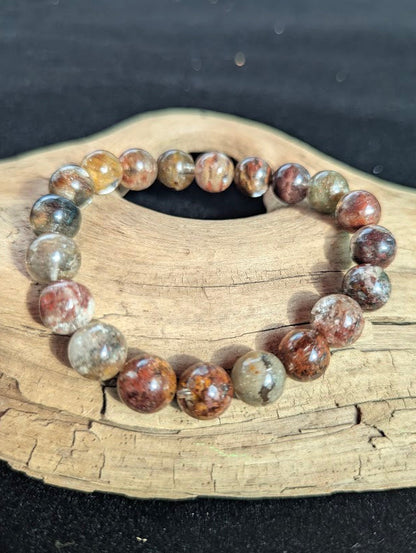 Intuitively selected 10mm AA Grade Four Season Garden Quartz beaded stretch bracelet displayed on driftwood.