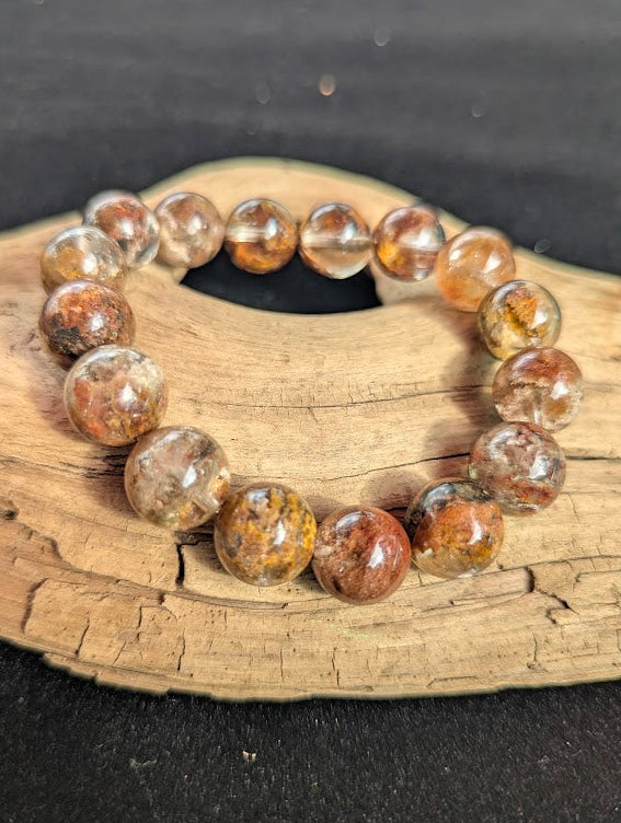 Intuitively selected 13mm AA Grade Four Season Garden Quartz beaded stretch bracelet resting on driftwood, showing large collector-grade spheres.