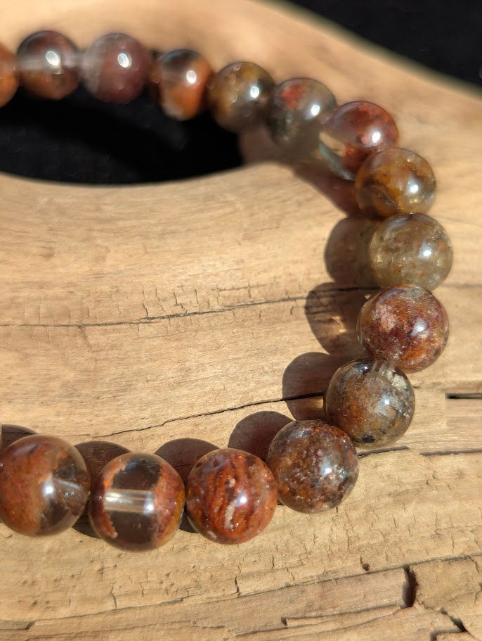 Macro detail of 9mm Lodolite beads showing the high vitreous lustre and dense earth-toned internal mineral formations.