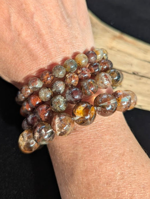 Stack of intuitively selected AA Grade Four Season Garden Quartz beaded bracelets worn together on a wrist demonstrating size progression and varied inclusion patterns.
