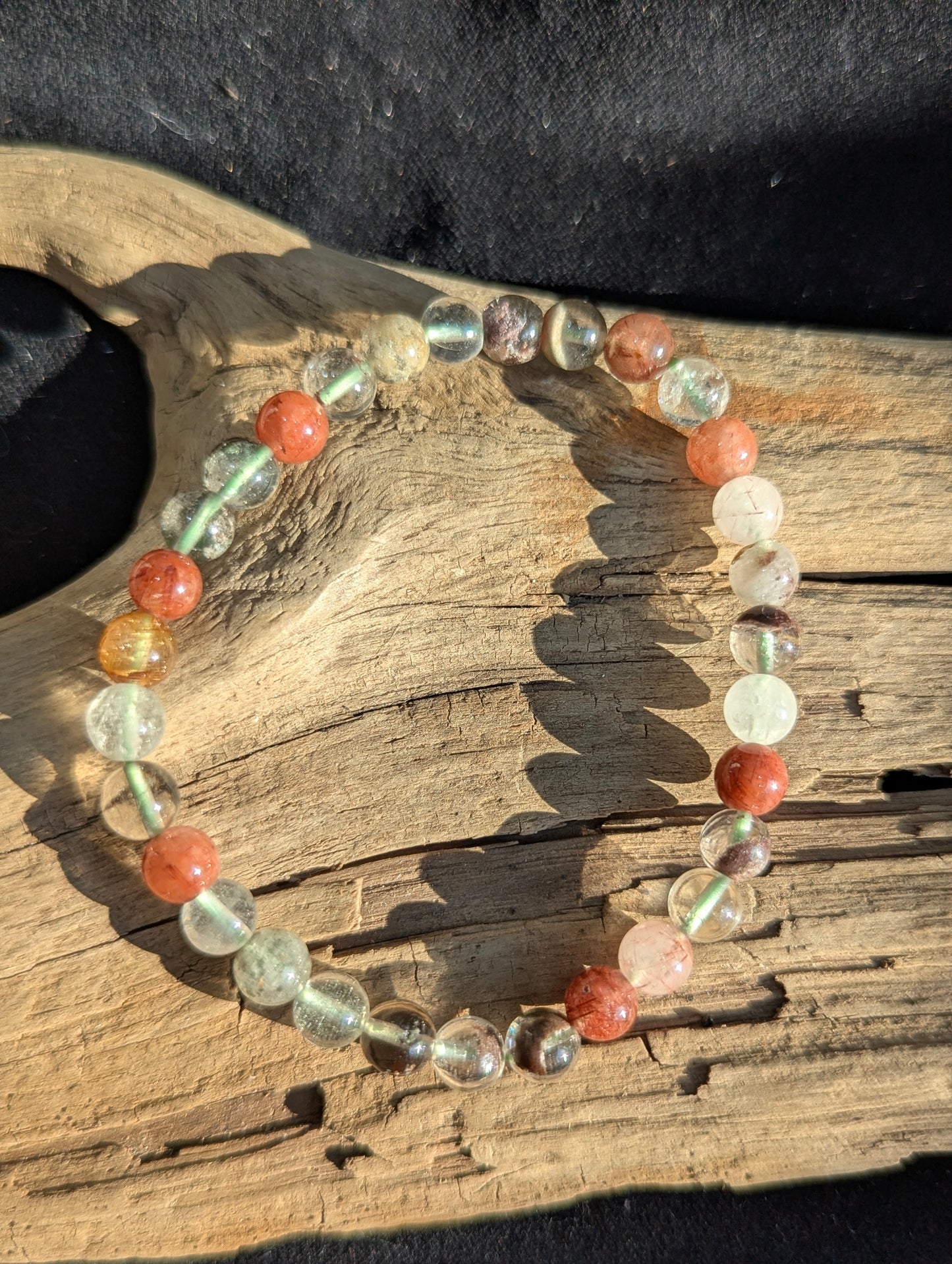 An all-natural 6mm Garden Quartz beaded stretch bracelet with rich green chlorite inclusions, displayed on a neutral surface to show bead uniformity.