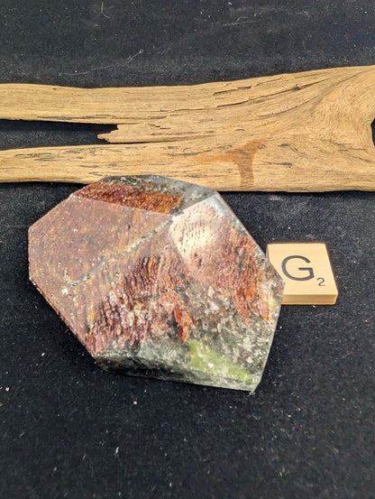 Exact piece Garden Quartz faceted freeform, Variant G2, dominated by a wide, textured layer of ribbed, rust-red iron oxide inclusions.