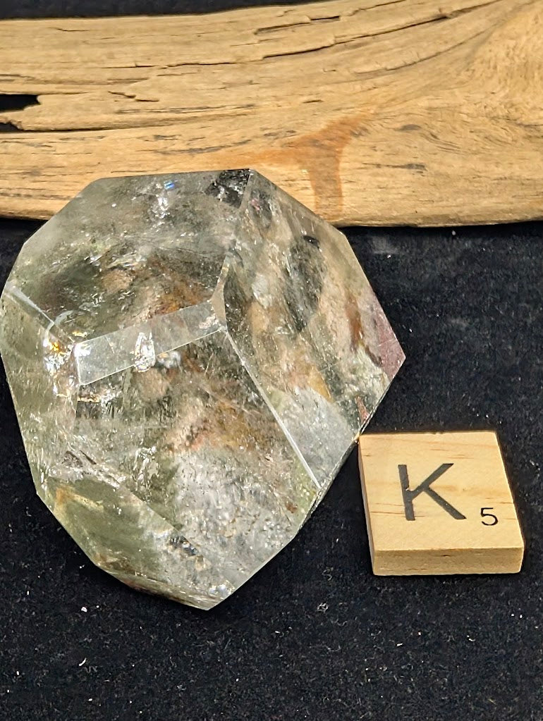 Exact piece Garden Quartz faceted freeform, Variant K5, showcasing high optical clarity above a distinct, suspended cluster of green chlorite moss.