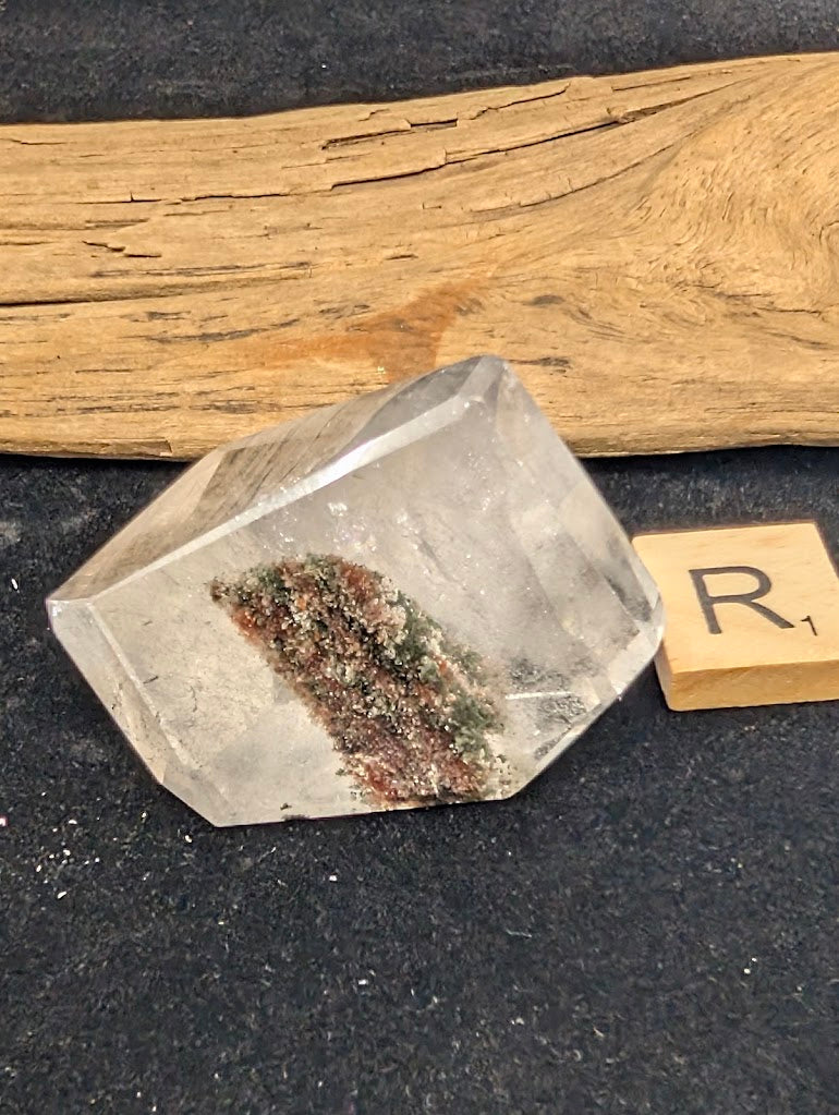 Exact piece Garden Quartz broad freeform, displaying high clarity above a striking, dense cluster of green and red minerals at the base.