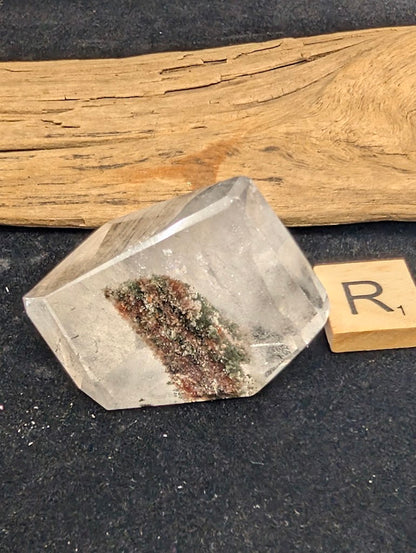 Exact piece Garden Quartz broad freeform, displaying high clarity above a striking, dense cluster of green and red minerals at the base.