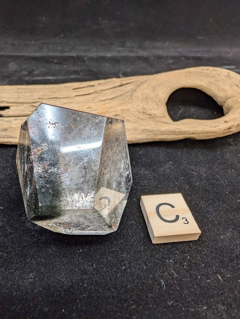 Exact piece Garden Quartz faceted freeform, displaying high clarity quartz contrasting with deep green chlorite deposits.