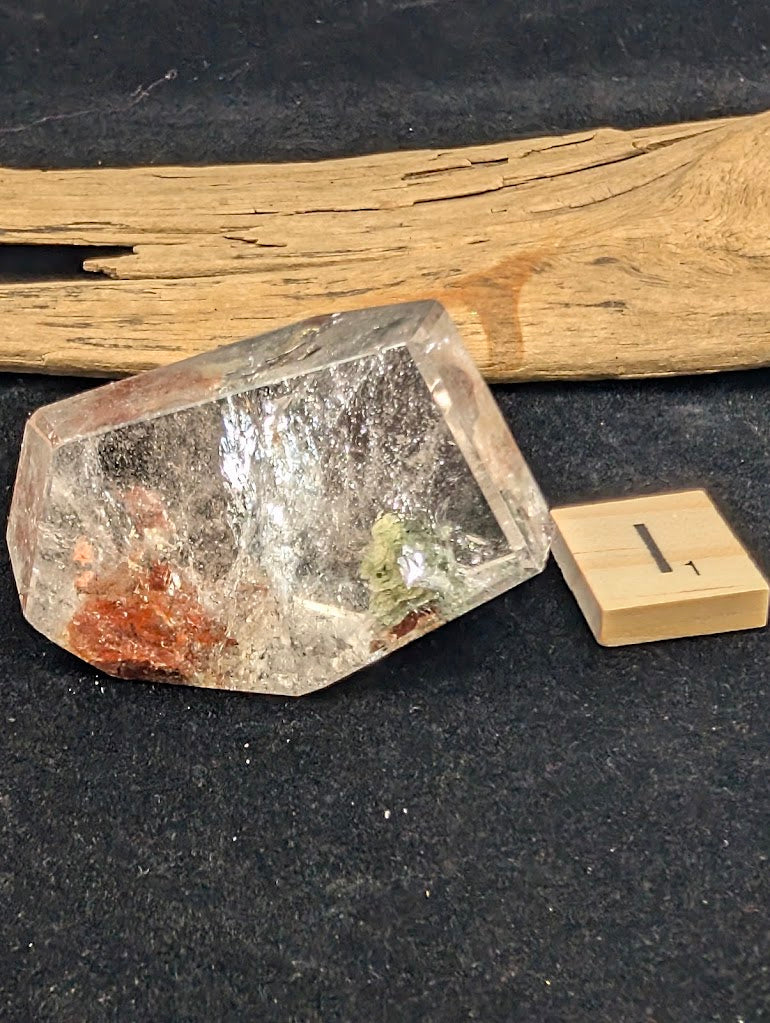 Exact piece Garden Quartz elongated faceted cut, showcasing two distinct, dense inclusion clusters in red and green.