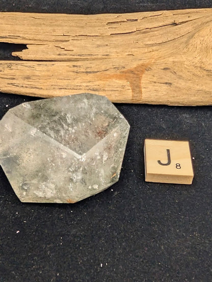 Exact piece Garden Quartz broad faceted freeform, characterized by dispersed green chlorite moss and red iron oxide patches.
