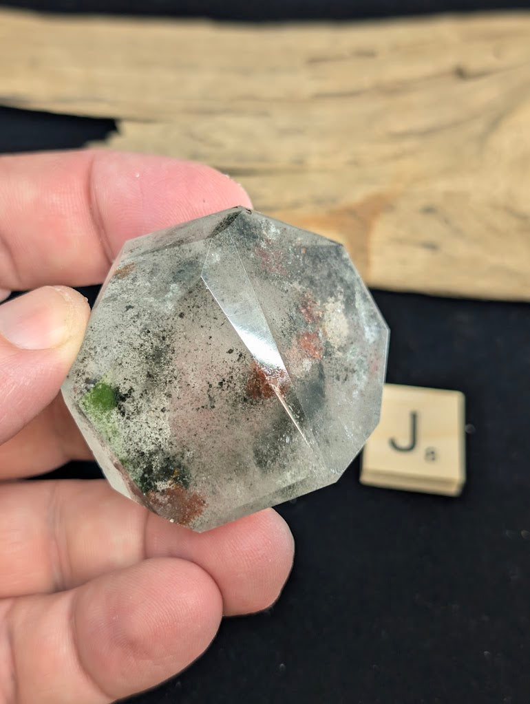 Exact piece Garden Quartz broad faceted freeform, characterized by dispersed green chlorite moss and red iron oxide patches.