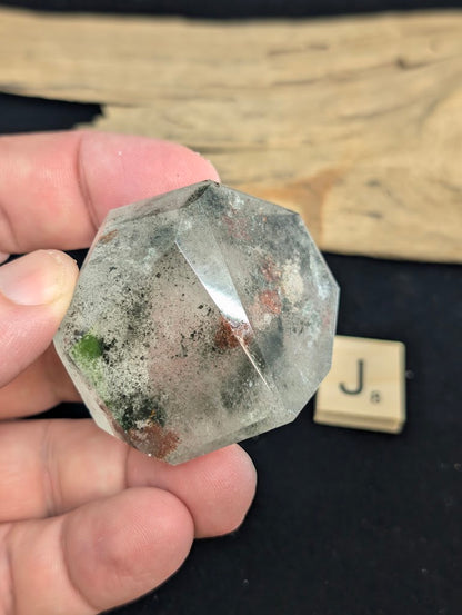 Exact piece Garden Quartz broad faceted freeform, characterized by dispersed green chlorite moss and red iron oxide patches.