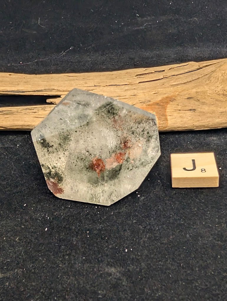 Exact piece Garden Quartz broad faceted freeform, characterized by dispersed green chlorite moss and red iron oxide patches.