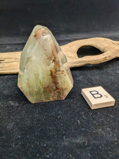 Exact piece Garden Quartz faceted freeform, featuring golden-green chlorite mixed with reddish-brown iron oxide inclusions.