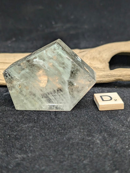 Exact piece Garden Quartz faceted freeform with a pentagonal face, showing white mineral deposits and red iron oxide.
