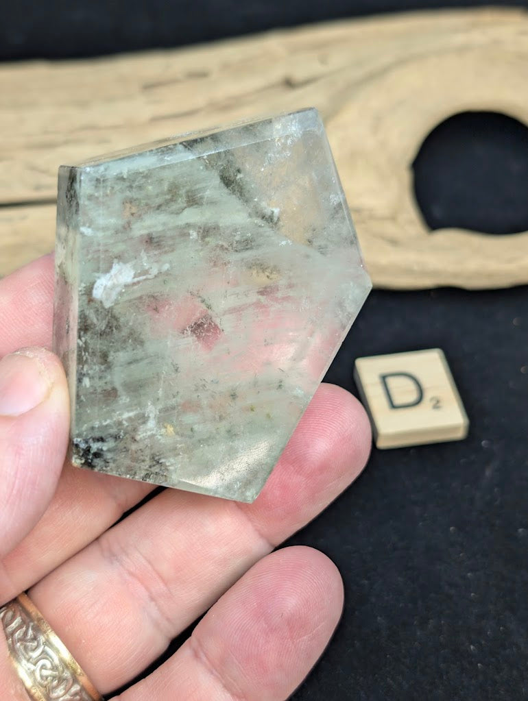 Exact piece Garden Quartz faceted freeform with a pentagonal face, showing white mineral deposits and red iron oxide.