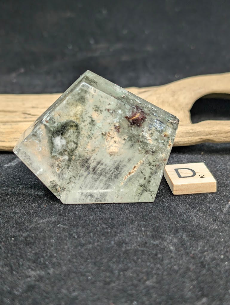 Exact piece Garden Quartz faceted freeform with a pentagonal face, showing white mineral deposits and red iron oxide.