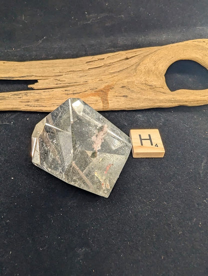 Exact piece Garden Quartz faceted freeform, highly transparent with delicate, sparse pinkish-red and green suspended wisps.