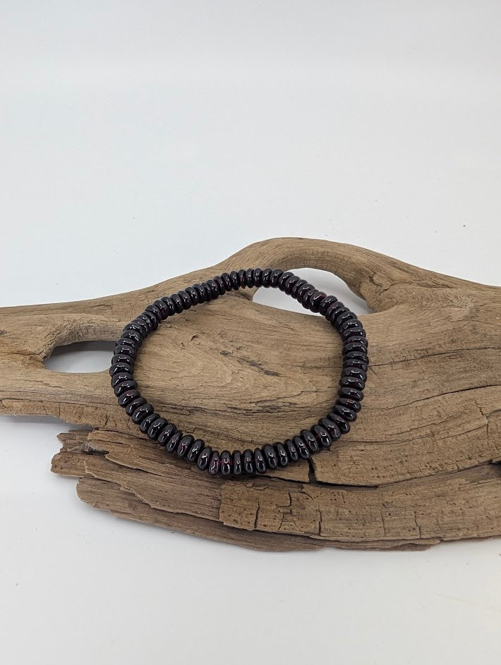 Garnet 5.5 mm heishi bracelet on driftwood, deep wine-red polish