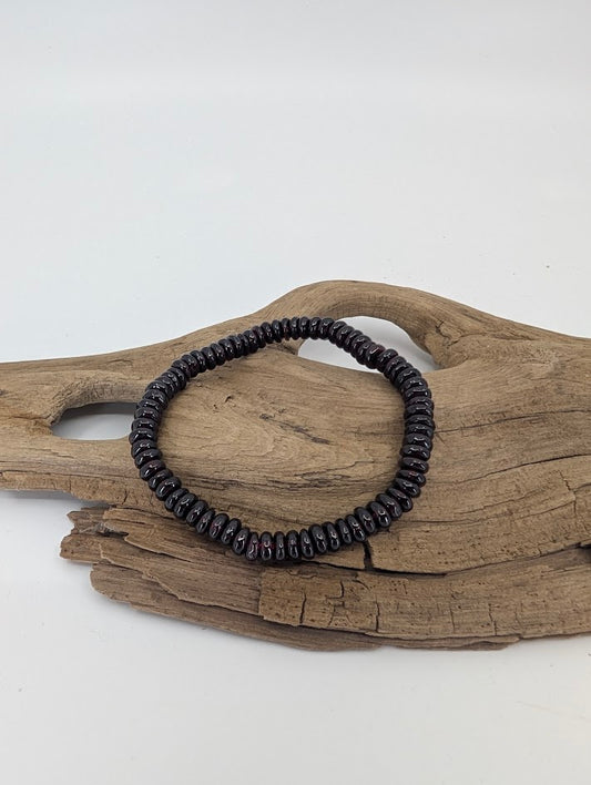 Garnet 5.5 mm heishi bracelet on driftwood, deep wine-red polish